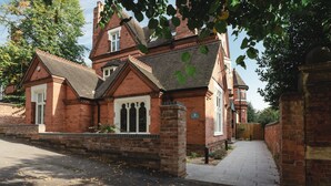 A traditional brick building with a prominent tower, a gated entrance, and a paved pathway leading to the main entrance. - Stunning upstairs flat in The Park neighbourhood (Nottingham)