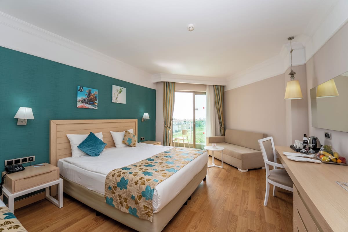 Camera d'albergo con letto, comodino, lampada, sedia e scrivania con specchio.