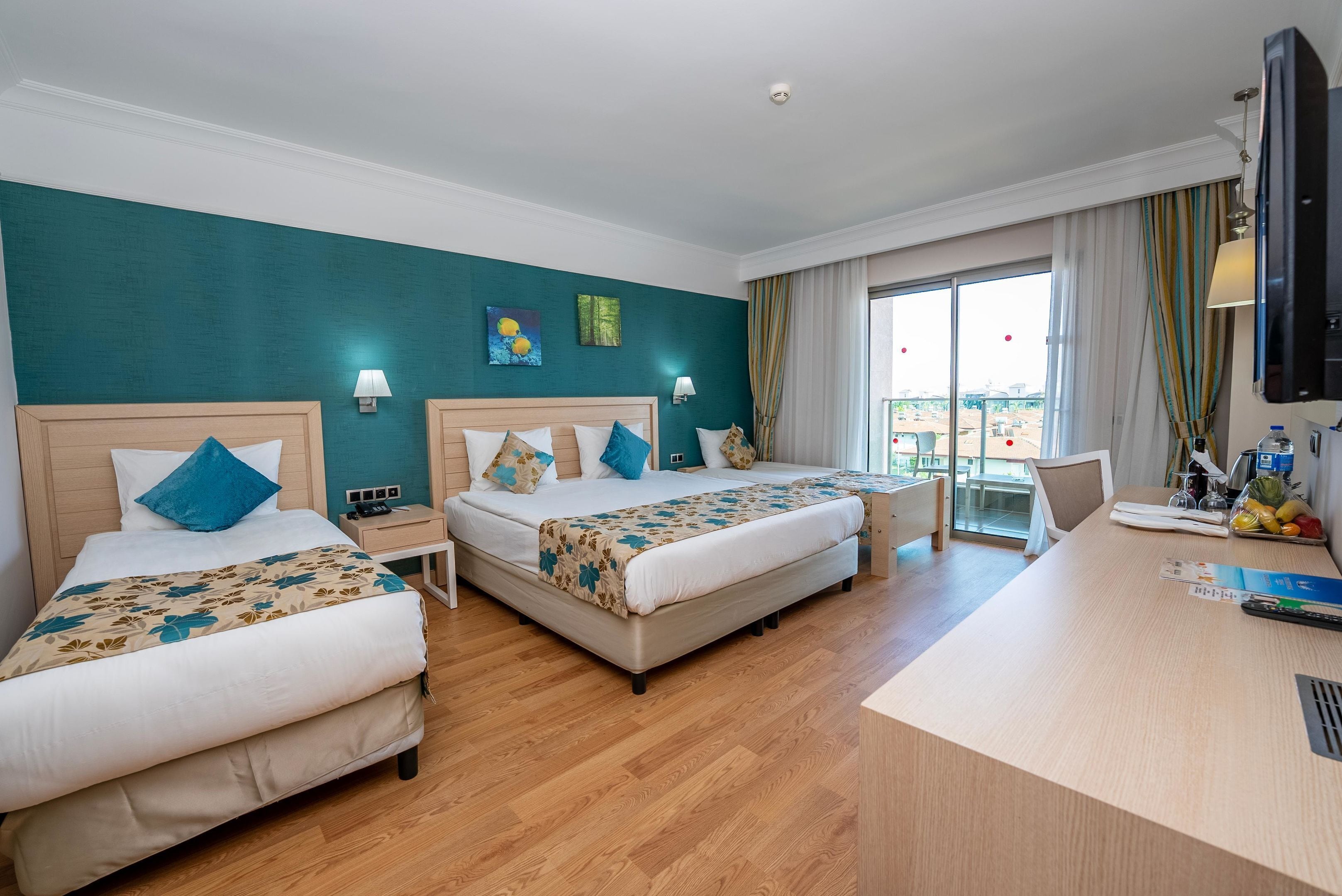 A hotel room with two beds, a desk, and a view of the city.