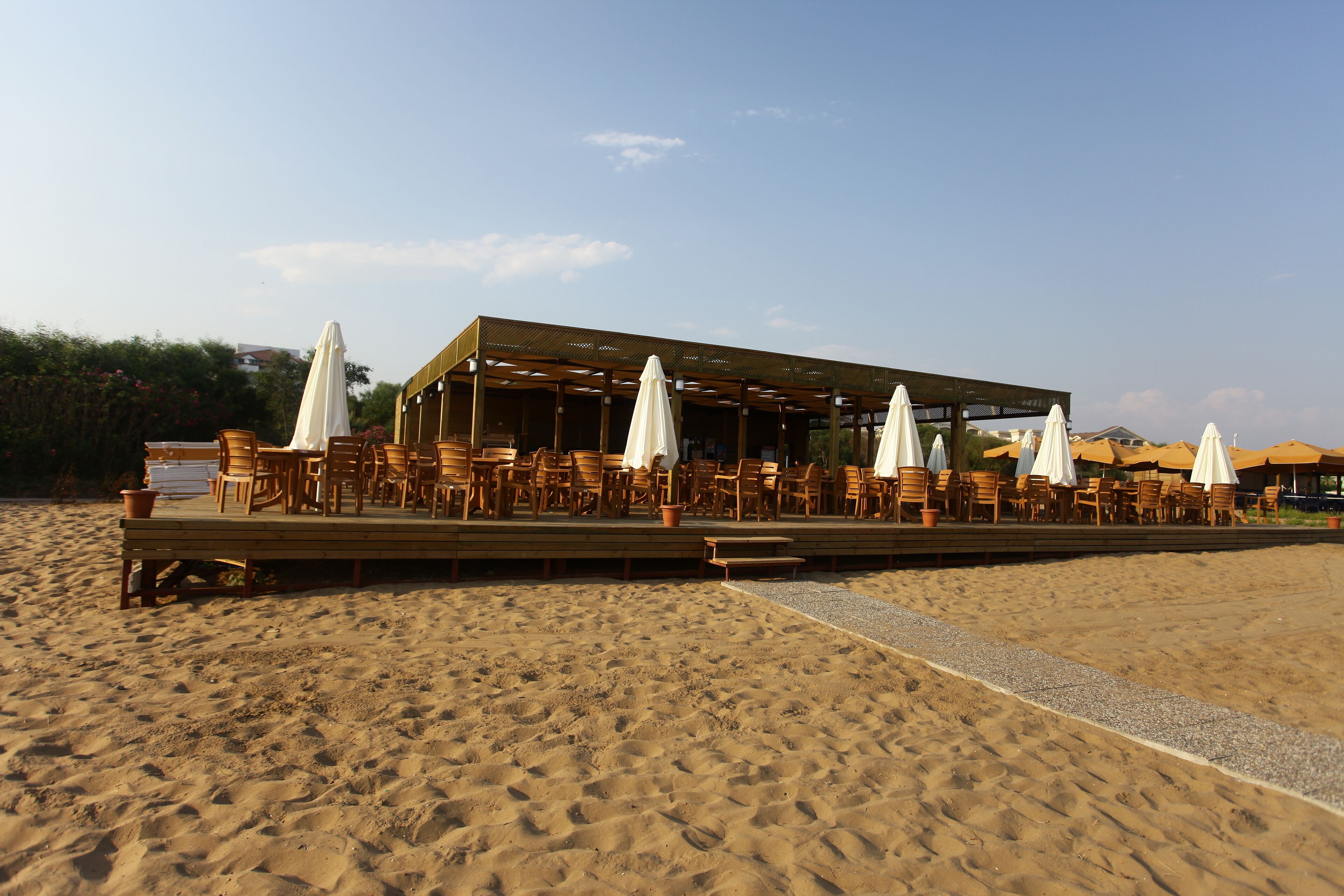 A beachside restaurant with outdoor seating and umbrellas.