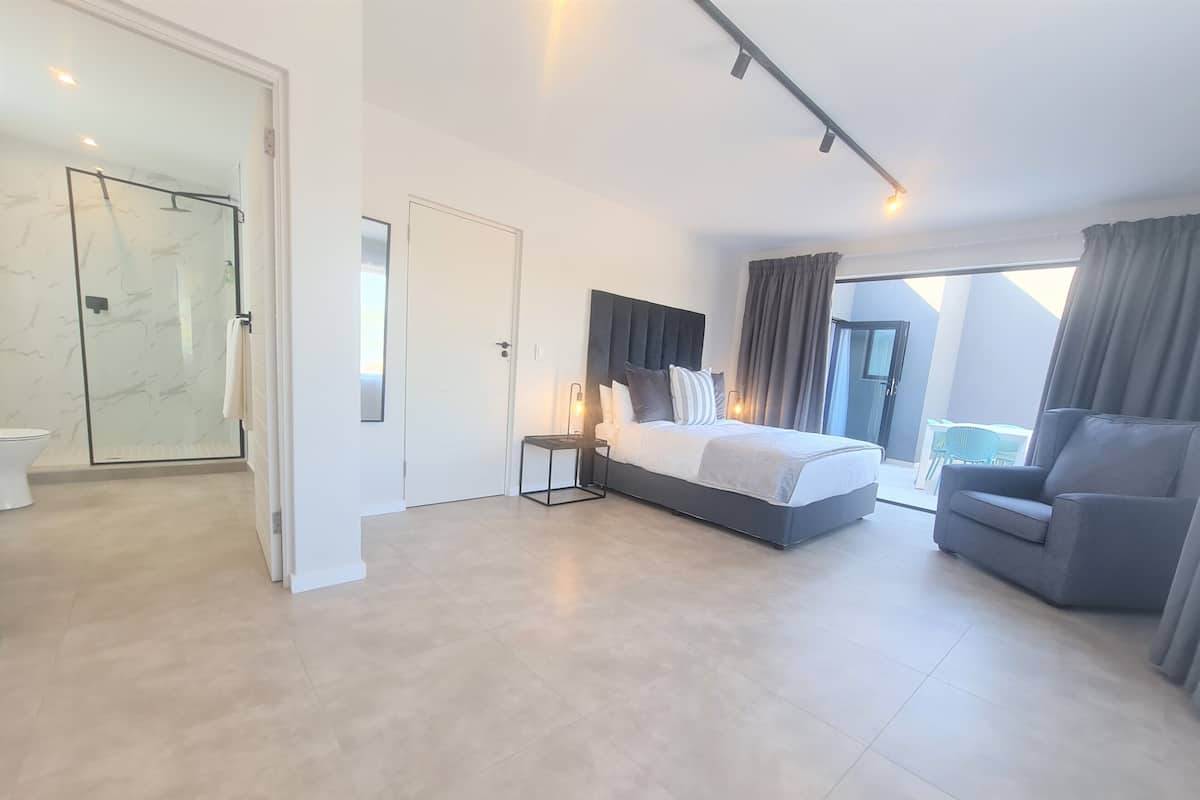Een moderne slaapkamer met een groot bed, een zithoek en een douchecabine van glas.