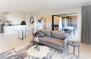 Uma sala de estar moderna com sofá, mesa de centro e área de jantar com cadeiras e mesa.