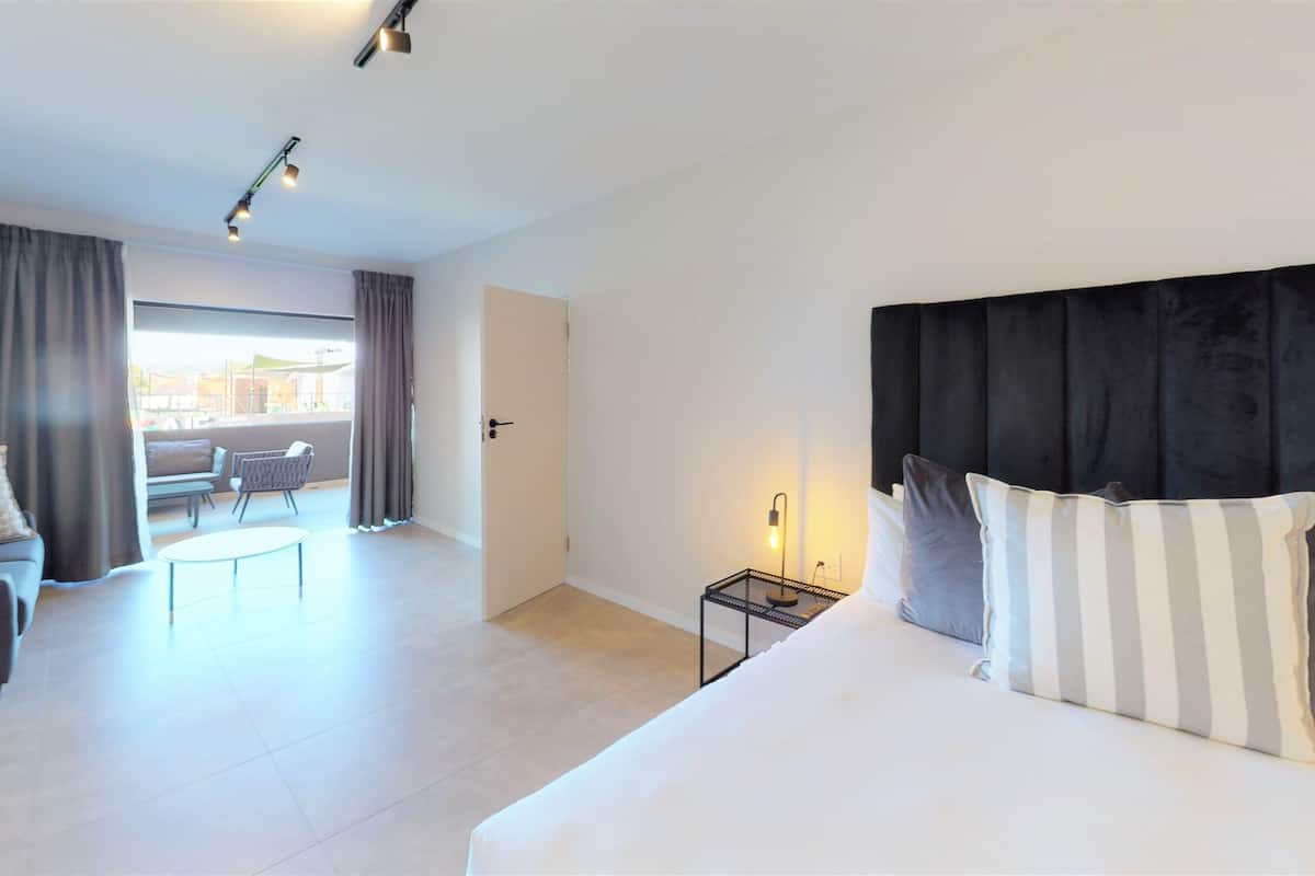 Een moderne hotelkamer met een groot bed, een slaapbank, een kleine tafel en uitzicht.