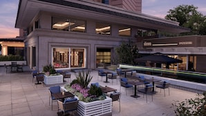 An outdoor patio area with seating, a restaurant, and a view of the building's facade. - Divan Ankara (Ankara)