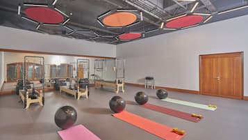 A spacious gym with exercise equipment, yoga mats, and large mirrors.
