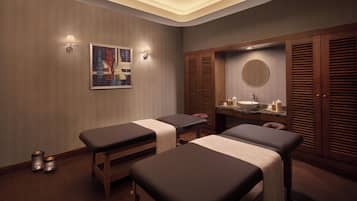 Ett spa-rum med två massagebänkar, ett handfat och en spegel.