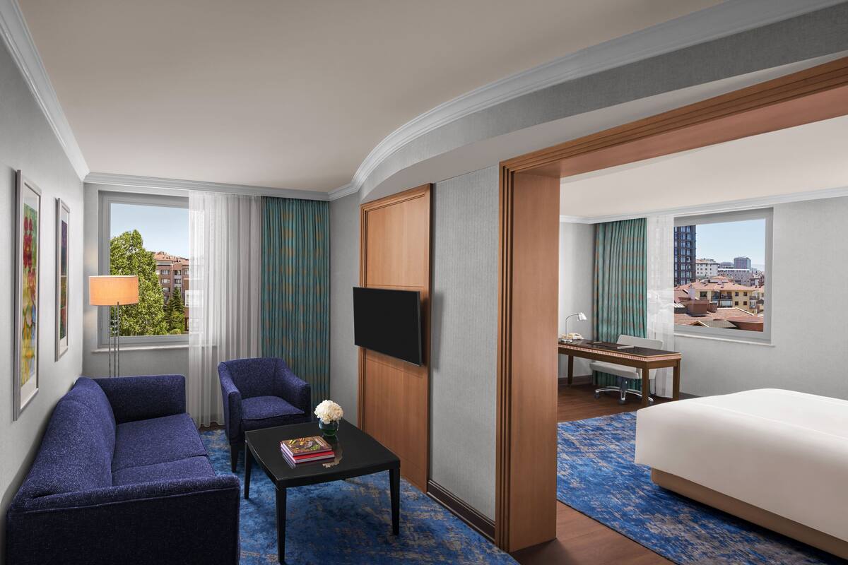 Una habitación de hotel con una cama, un sofá, un escritorio y un televisor.