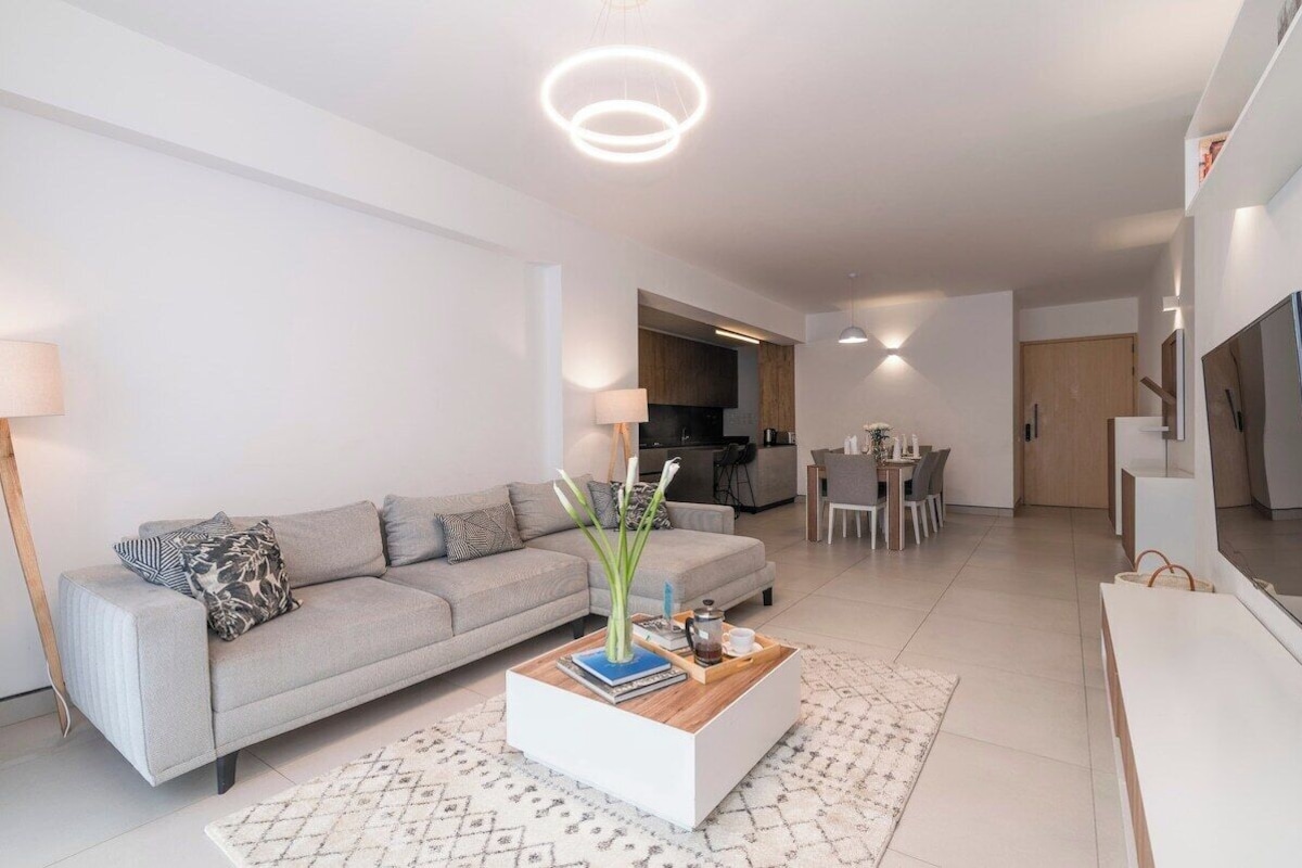A modern living room with a sofa, coffee table, and dining area.