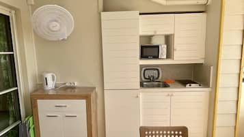 A compact kitchenette with a microwave, sink, and a small cabinet.