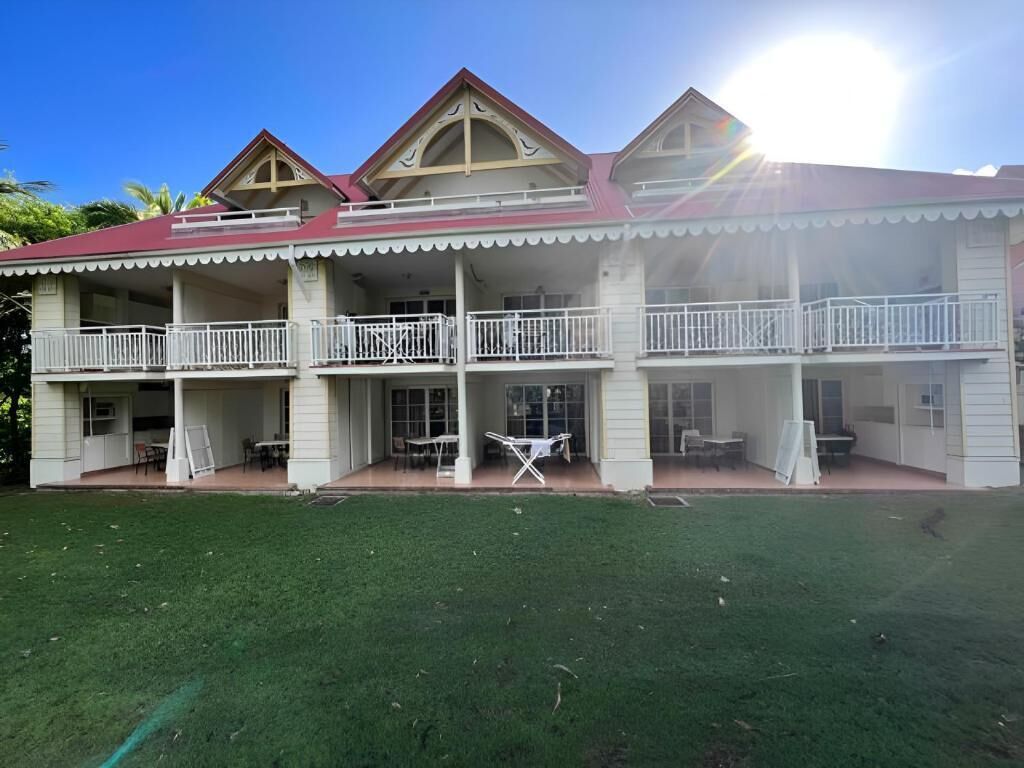 A two-story building with a red roof and white exterior. It has a balcony on the upper floor and a covered patio area on the ground floor.