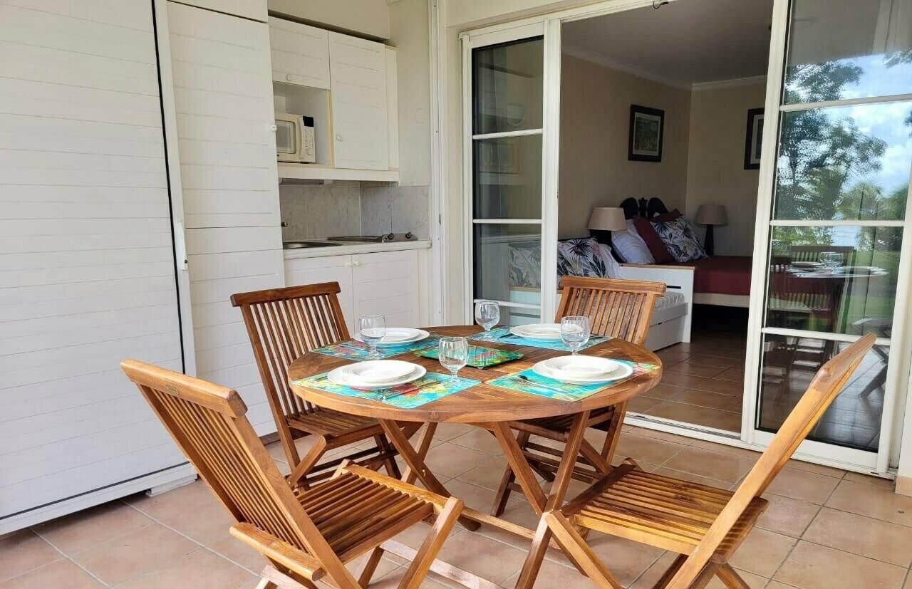 A dining area with a round wooden table set for four, surrounded by wooden chairs.