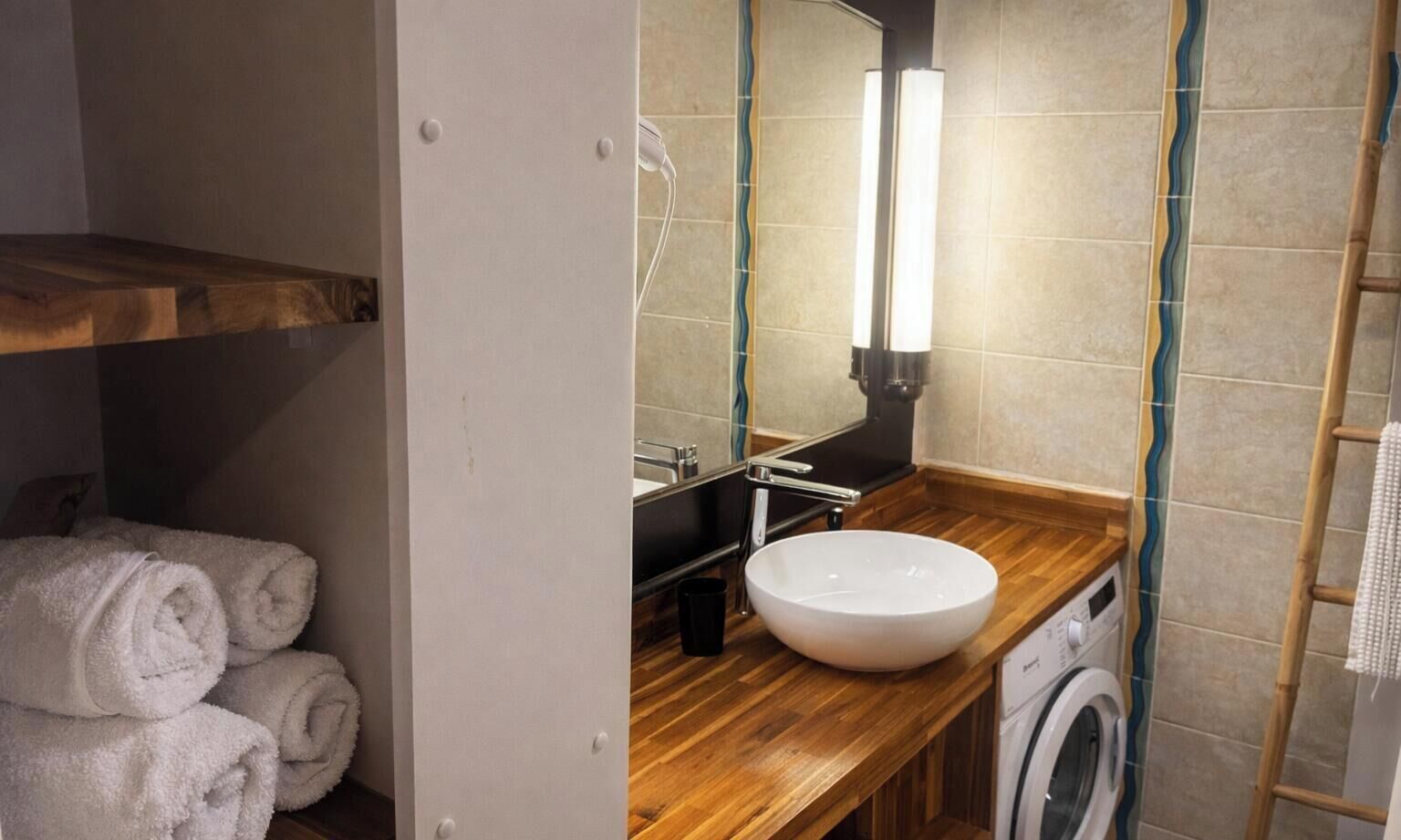 Une petite salle de bain avec un meuble-lavabo en bois, un évier, un lave-linge et un porte-serviettes.