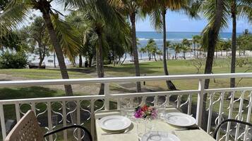 Une table dressée pour deux personnes, avec vue sur la plage et l’océan.