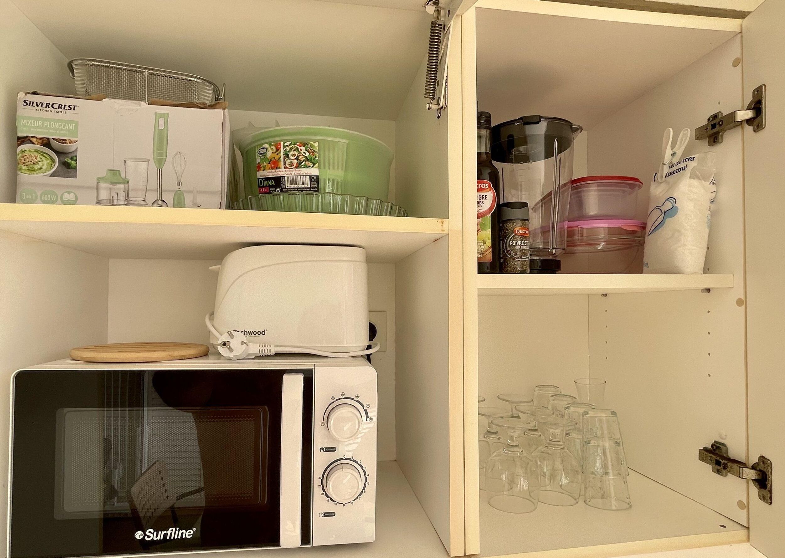 A kitchen with a microwave, a toaster, and a blender on the counter.