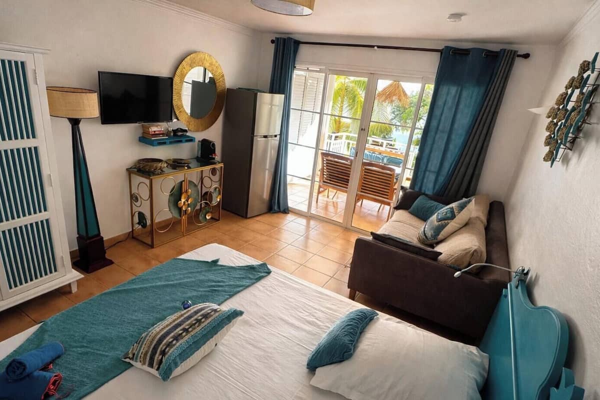 Ein Schlafzimmer mit Bett, Schrank, Fernseher, Spiegel und Blick nach draußen.