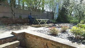 Eine steinerne Treppe führt zu einer erhöhten Plattform mit Tisch und Stühlen.