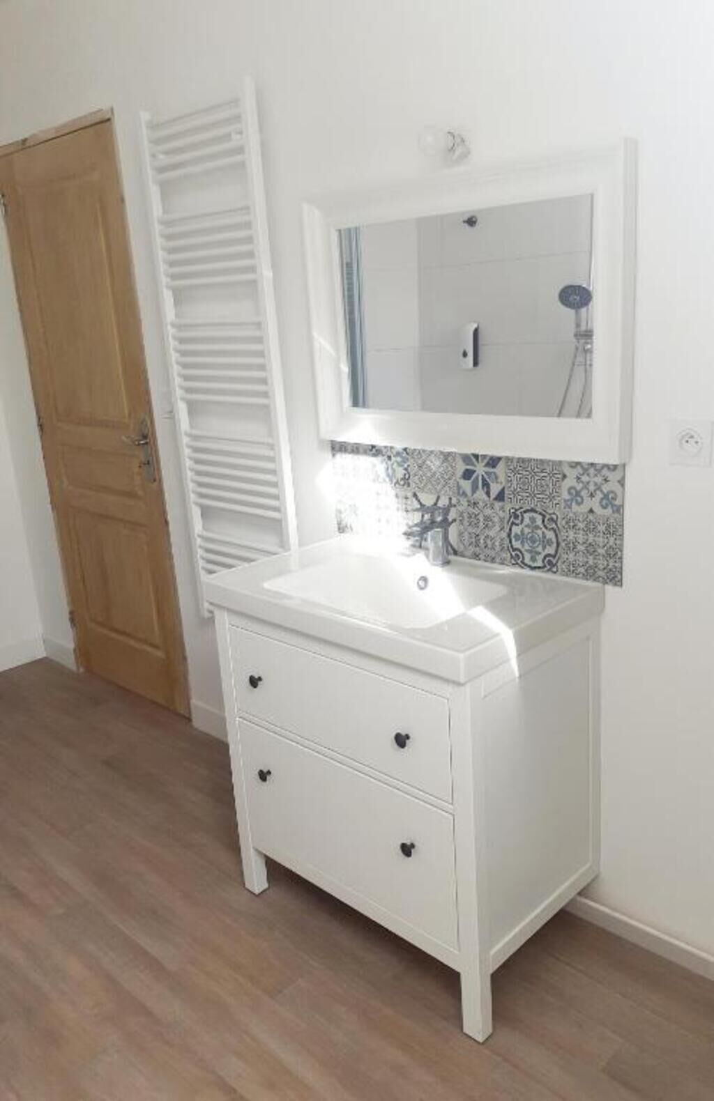 A white bathroom vanity with a mirror, a sink, and two drawers.