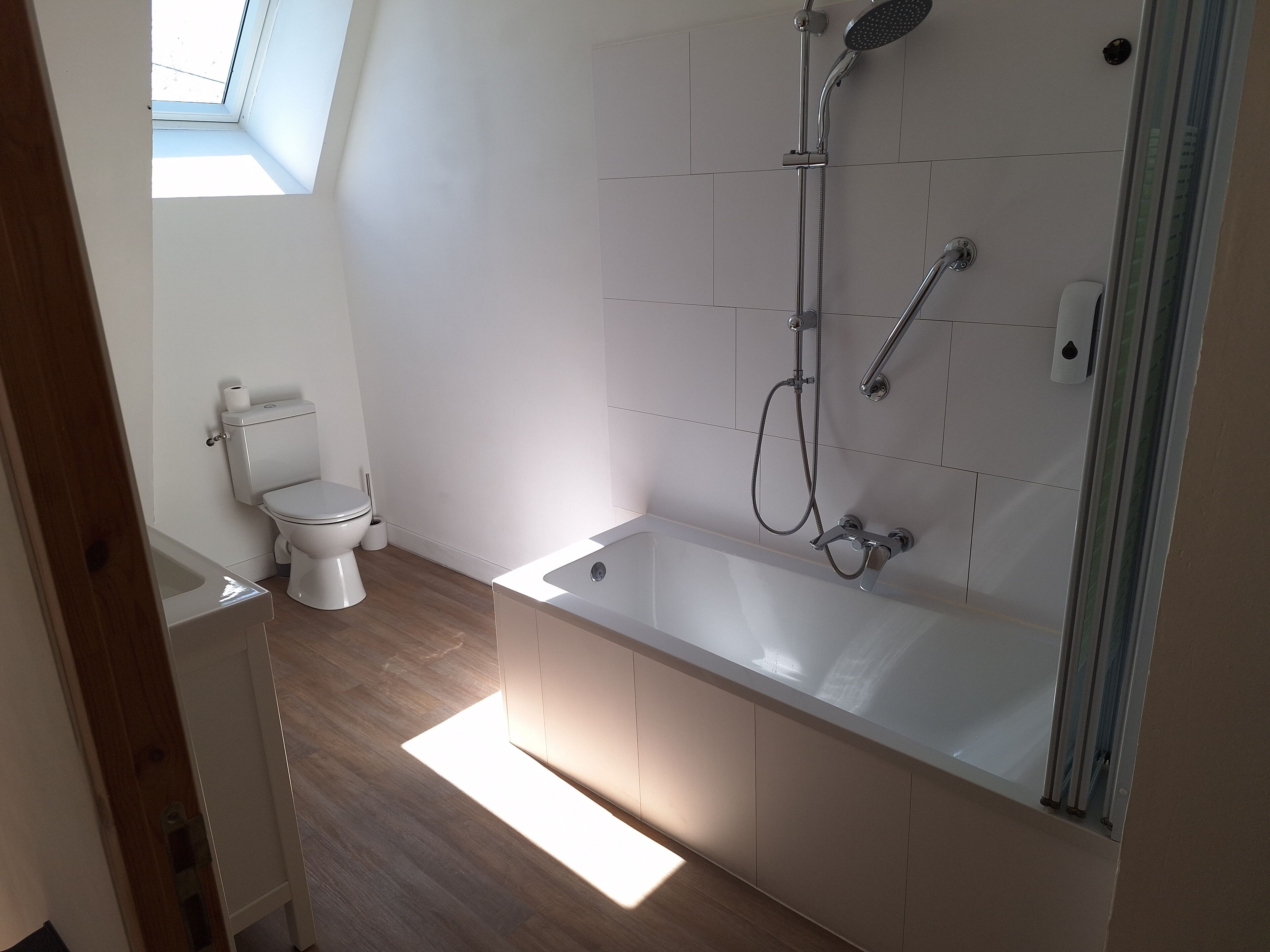 A modern bathroom with a toilet, a bathtub, and a shower.