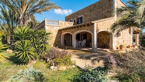A stone building with a courtyard, featuring arches and a seating area. - Villa with pool very close to Es Trenc Beach (Campos)
