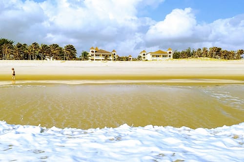 Na praia, areia branca, barracas de praia de cortesia, espreguiçadeiras