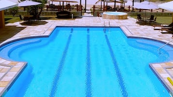 Una piscina al aire libre, sombrillas, sillones reclinables de piscina