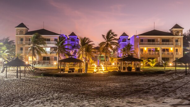 A beachfront hotel with multiple balconies, palm trees, and outdoor seating areas. - Atlantic Palace Family inn (Aquiraz)