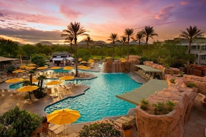 Ein Poolbereich eines Resorts mit mehreren Pools, Liegestühlen und Sonnenschirmen.