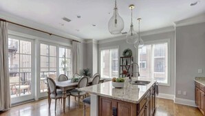 A spacious kitchen with a large island, wooden cabinets, and pendant lighting. - Luxury Bay Street Condo featuring Dual King Suites (Savannah)