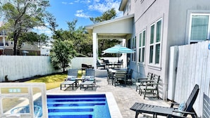 A backyard with a swimming pool, outdoor furniture, and a covered patio area.