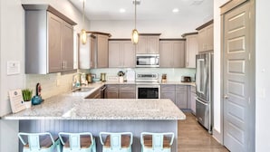 A modern kitchen with granite countertops, stainless steel appliances, and light wood cabinets.