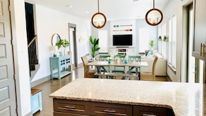 A modern kitchen with granite countertops, a dining area with a table and chairs, and a staircase leading to another level.