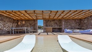 A pool area with a pergola, stone walls, and seating. - Villa Retreat (Milos)