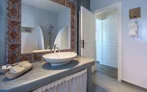 A bathroom with a large mirror, a white sink, and a shower. There is a towel rack and a small framed picture on the wall. - Villa Retreat (Milos)