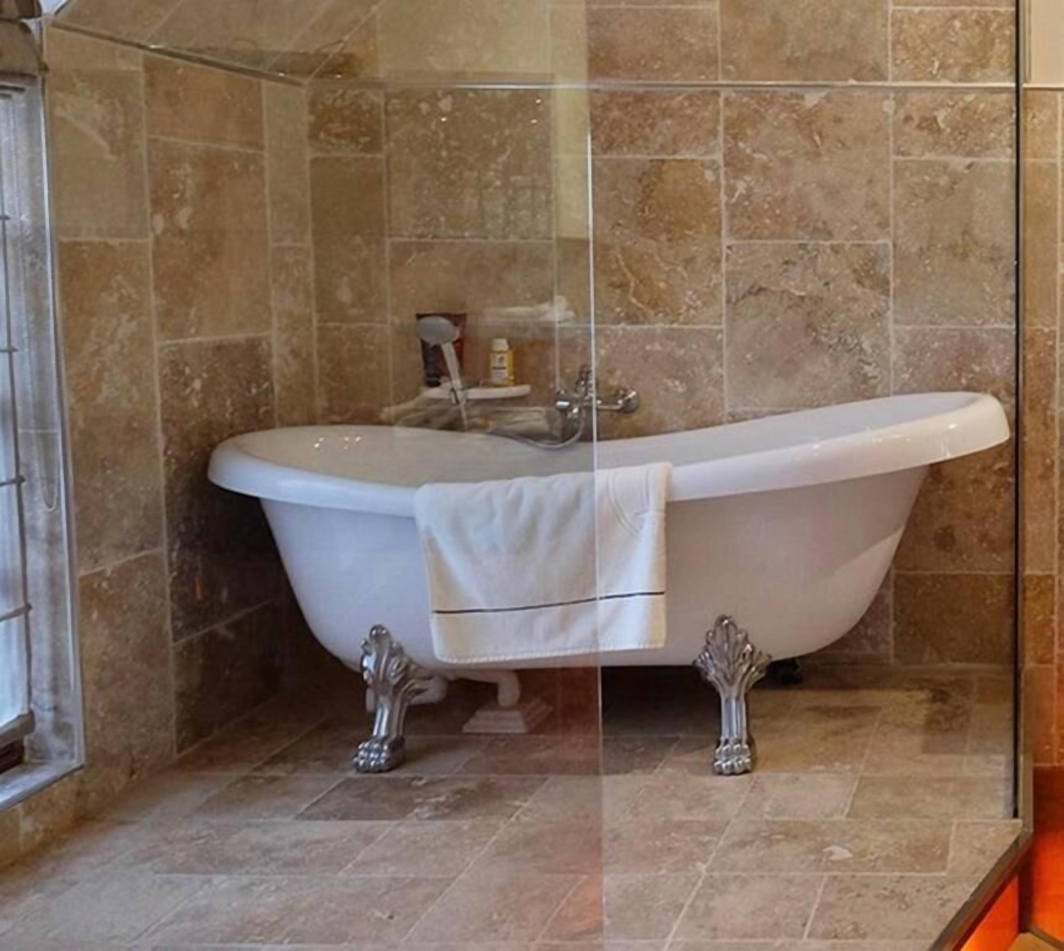 A bathroom with a freestanding bathtub, a glass shower enclosure, and a tiled floor.