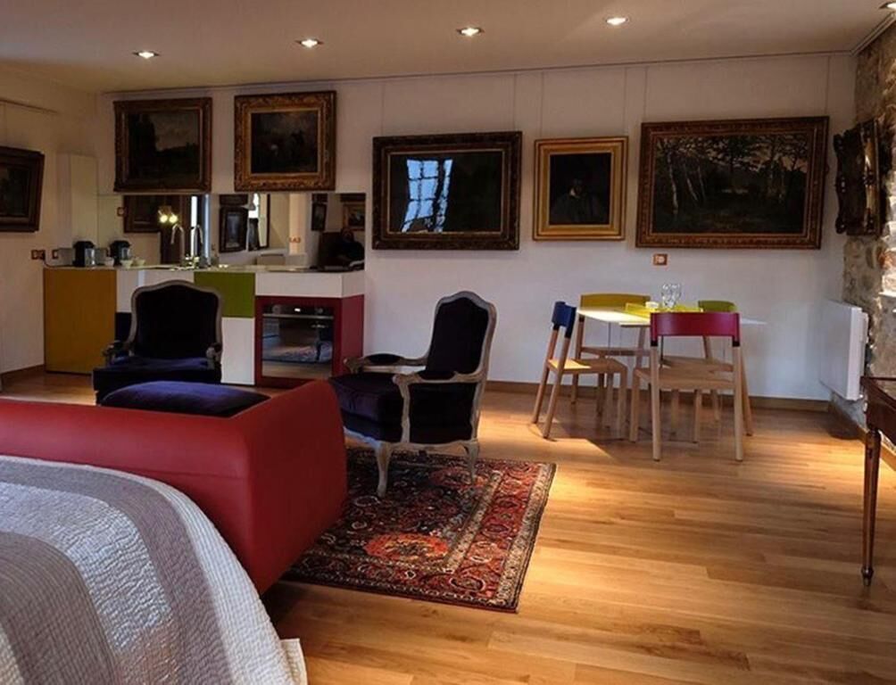 Una habitación con cama, escritorio, sillas y mesa de comedor. En la pared hay cuadros enmarcados.