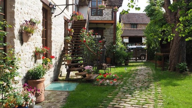 Une cour avec un chemin en pierre, un escalier en bois et des plantes en pot.