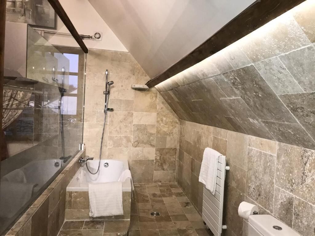 Een badkamer met een douche met glazen wand, een bad en een toilet.
