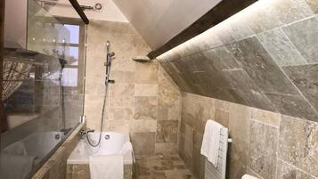 Een badkamer met een douche met glazen wand, een bad en een toilet.