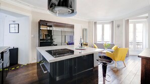 Een moderne keuken met een centraal eiland, zwarte kasten en een grote zwarte hanglamp.