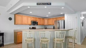 A modern kitchen with wooden cabinets, stainless steel appliances, and a central island with bar stools.