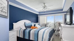 A hotel room with a bed, a desk, a chair, a television, and a window with blinds.