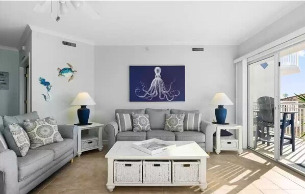 Una sala de estar moderna con un sofá gris, una mesa de centro blanca y decoración en la pared.