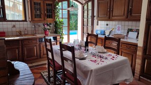 A kitchen with wooden cabinets, a dining table set with white tablecloth and plates, and a window with curtains. - CHARMING VILLA WITH PRIVATE POOL - Special Summer 2026 Discount (Allauch)