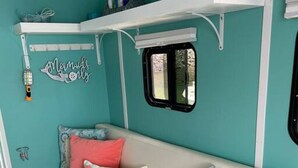 Un interior con temática turquesa, un sofá cama, almohadas y un ventanal.