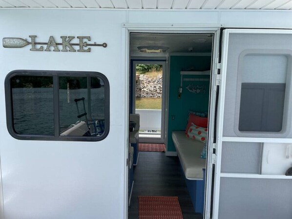 Una caravana con ventana, una puerta que da a un espacio exterior y una cama con almohadas.