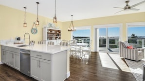 Una cocina moderna con una isla grande, armarios blancos e iluminación colgante.
