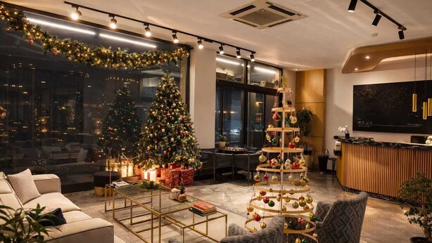 A modern hotel lobby with a large Christmas tree, a multi-tiered ornament tree, and a reception desk. - Moja City Hotel (Istanbul)