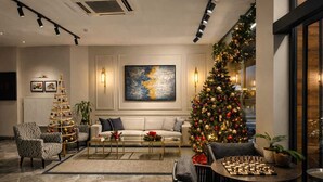 A modern living room with a Christmas tree, a sofa, armchairs, a coffee table, and a chessboard. - Moja City Hotel (Istanbul)