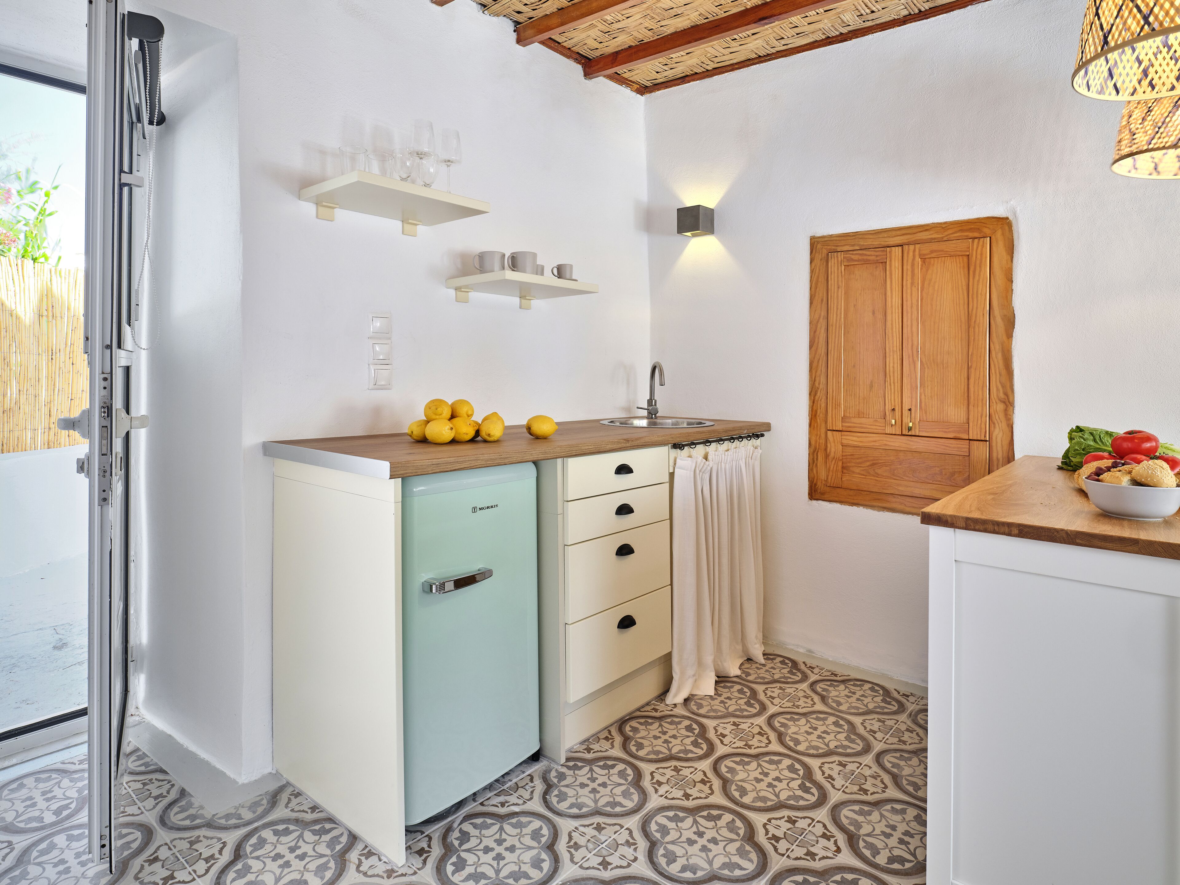 A compact kitchen with a built-in refrigerator, a sink, and a wooden countertop.