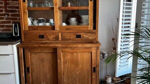 A wooden cabinet with glass doors containing kitchenware and decorative items. - Private rooftop 35m2, high-end apartment (Amsterdam)